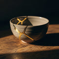 A close-up of a Kintsugi bowl, its cracks gracefully mended with gold, on a wooden surface. Jeremiah's promise of God's filling.