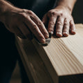 Craftsman's hands carefully sanding wood grain, illustrating 1 Corinthians 3:23 and Paul's teaching on Christ's ownership.