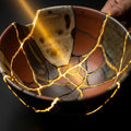 A beautifully mended ceramic bowl with glowing gold repairs, symbolizing healing and restoration.