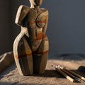 An abstract, unfinished sculpture in textured clay, softly lit, with sculpting tools nearby.