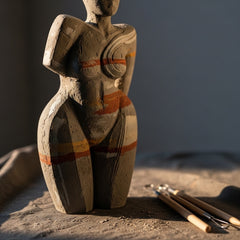 An abstract, unfinished sculpture in textured clay, softly lit, with sculpting tools nearby.