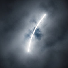An abstract image showing swirling grey mist being pierced by a brilliant white light.