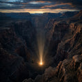 A vast, deep canyon from above, with a single, powerful point of light shining up from the bottom.