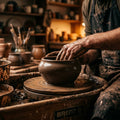 A potter's hands gently sculpting a piece of clay on a wheel, bathed in warm, focused light.