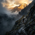A person climbing a mountain, moving from a dark, foggy valley toward a sunlit peak.