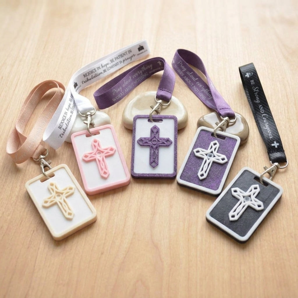 A collection of 3D-printed Eben Tags in various colors including Eben Navy and Heritage Blue, featuring raised ornate cross textures and fabric loops with scripture verses, designed as NFC-enabled touchpoints for daily devotions.