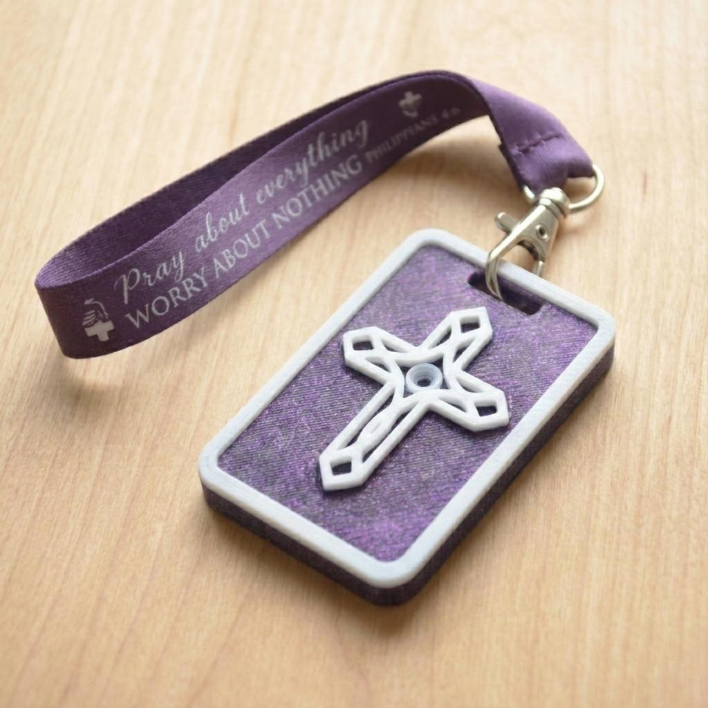 A 3D-printed Eben Tag in Metallic Purple featuring a raised ornate cross design. This NFC-enabled spiritual touchpoint includes a white border and is attached to a fabric lanyard printed with scripture, designed to trigger the Daily Eb devotional.