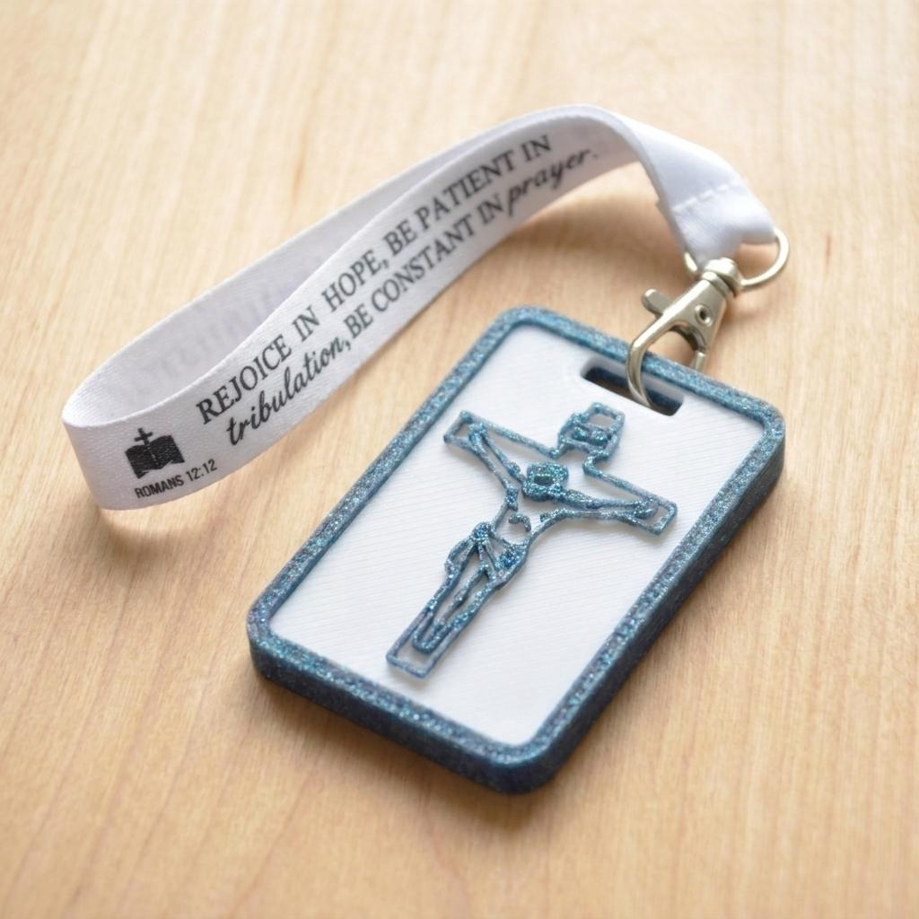 A 3D-printed Eben Tag in White and Blue featuring a raised crucifix design. This NFC-enabled spiritual touchpoint includes a metallic blue border and is attached to a fabric lanyard printed with scripture, designed to trigger the Daily Eb devotional.